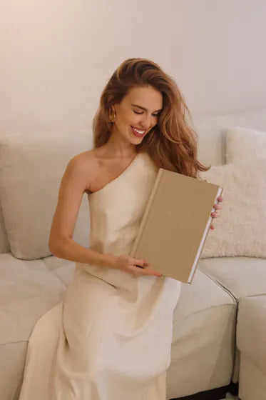 Cliente sorrindo com um álbum de capa bege nas mãos